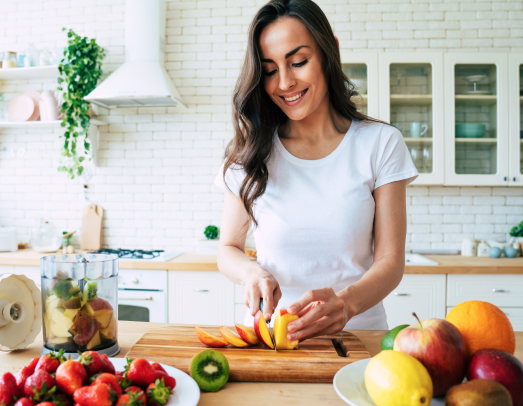 Woman in kitchen making fruit salad.