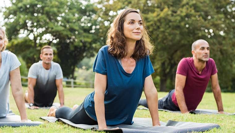 A joyful group of people exercising together outdoors during an outstation trip, radiating energy and camaraderie.