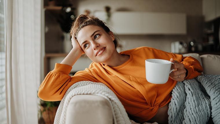 Woman sitting thoughtfully looking out of window, representing consideration of TPO Antibody testing.