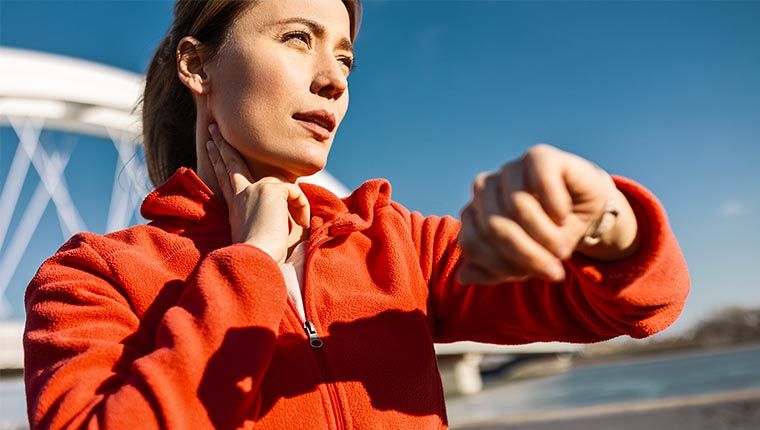 Woman checking her heart rate while exercising outside.