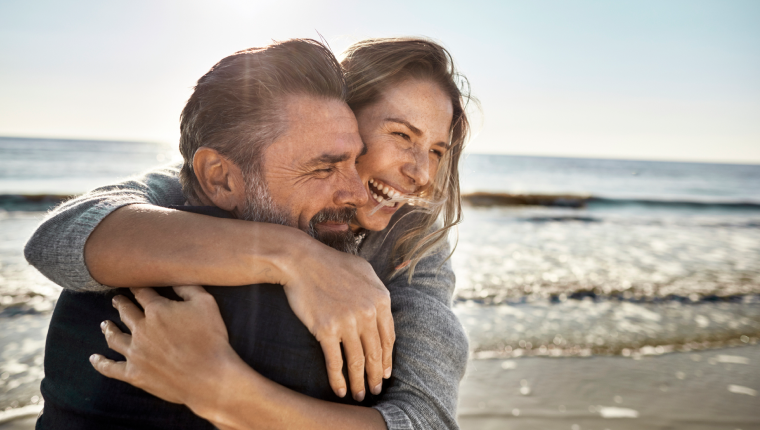Couple embraces on beach.