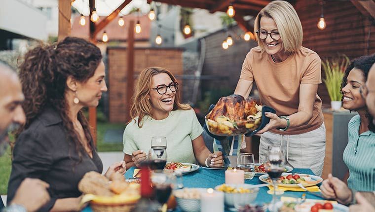 A happy group of people enjoying a keto friendly meal together outside.