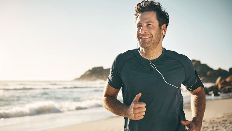 A smiling man running on the beach happy with his Custom Mens Health Test blood test results.