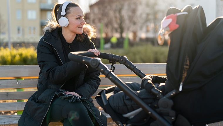 A woman wearing a headset is happily listening to music.