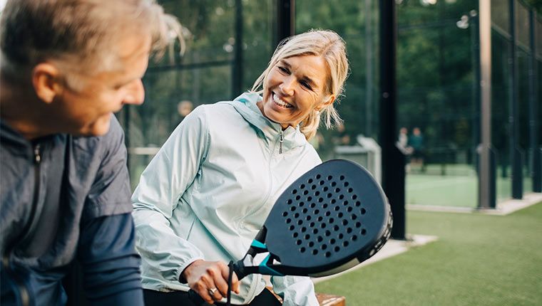 A woman smiles while playing pickleball improving her health.