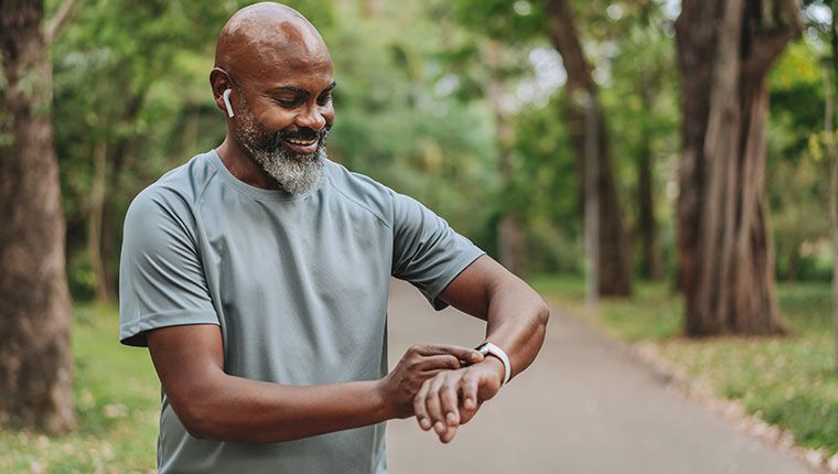 Man outdoors checking health watch.