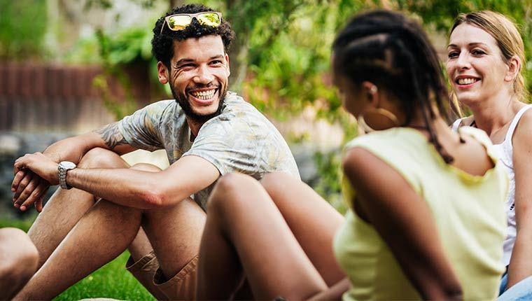 Man sitting outside socializing with friends outdoors, representing consideration of Free T3 Testing.