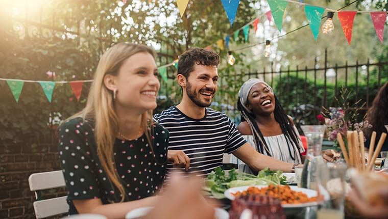 Friends sharing a meal outside together at a dining table.