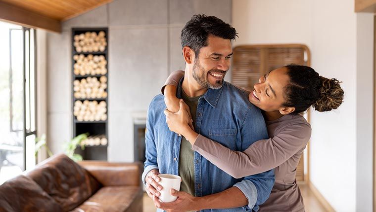 A couple in a loving embrace in their living room, representing comfort while discussing herpes antibody test results.