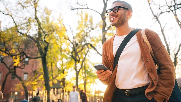 A happy man walking with his phone after checking his test results.