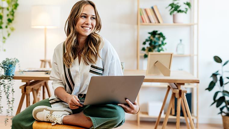 A happy woman sitting with a laptop in her home after seeing her test results.
