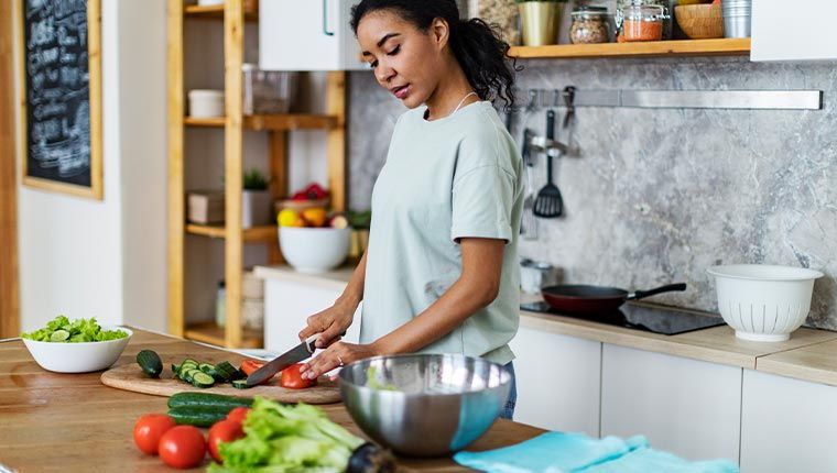 Woman chopping vegetables maintain selenium levels for health and wellness.