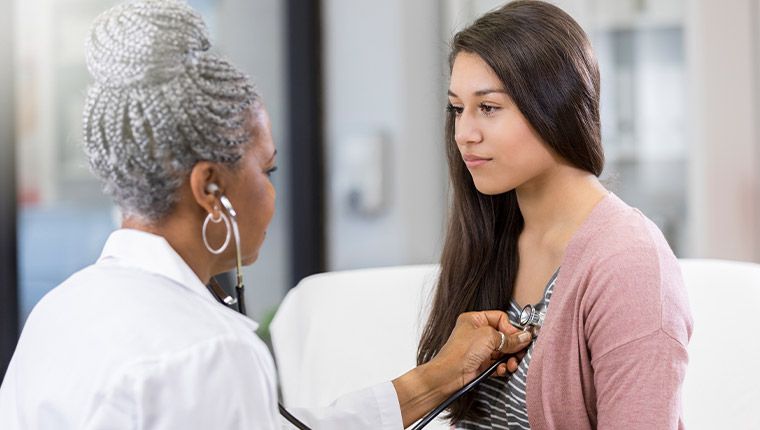Doctor examines college-aged patient.