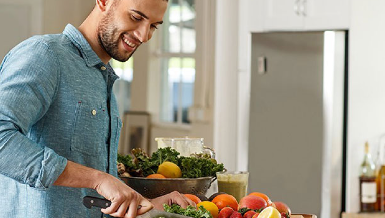 Man in kitchen making salad.