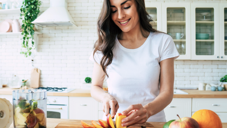 Woman in kitchen making fruit salad.